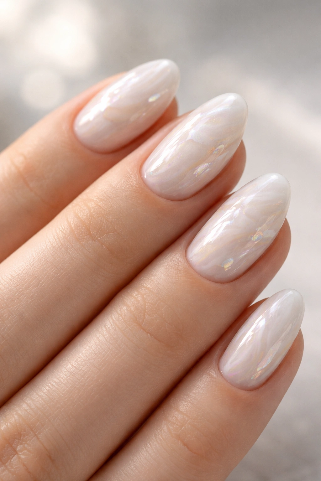 Close-up of pearl marble nails with a sheer glow on short almonds