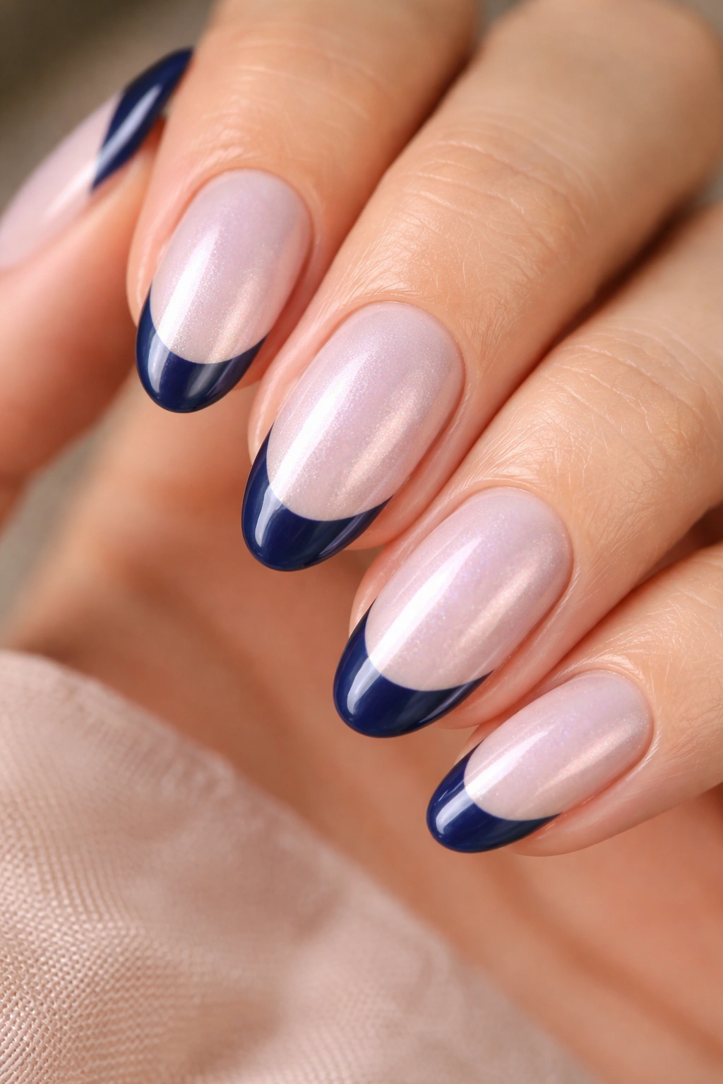 Close-up of short almond nail with pearl shimmer base and navy tip