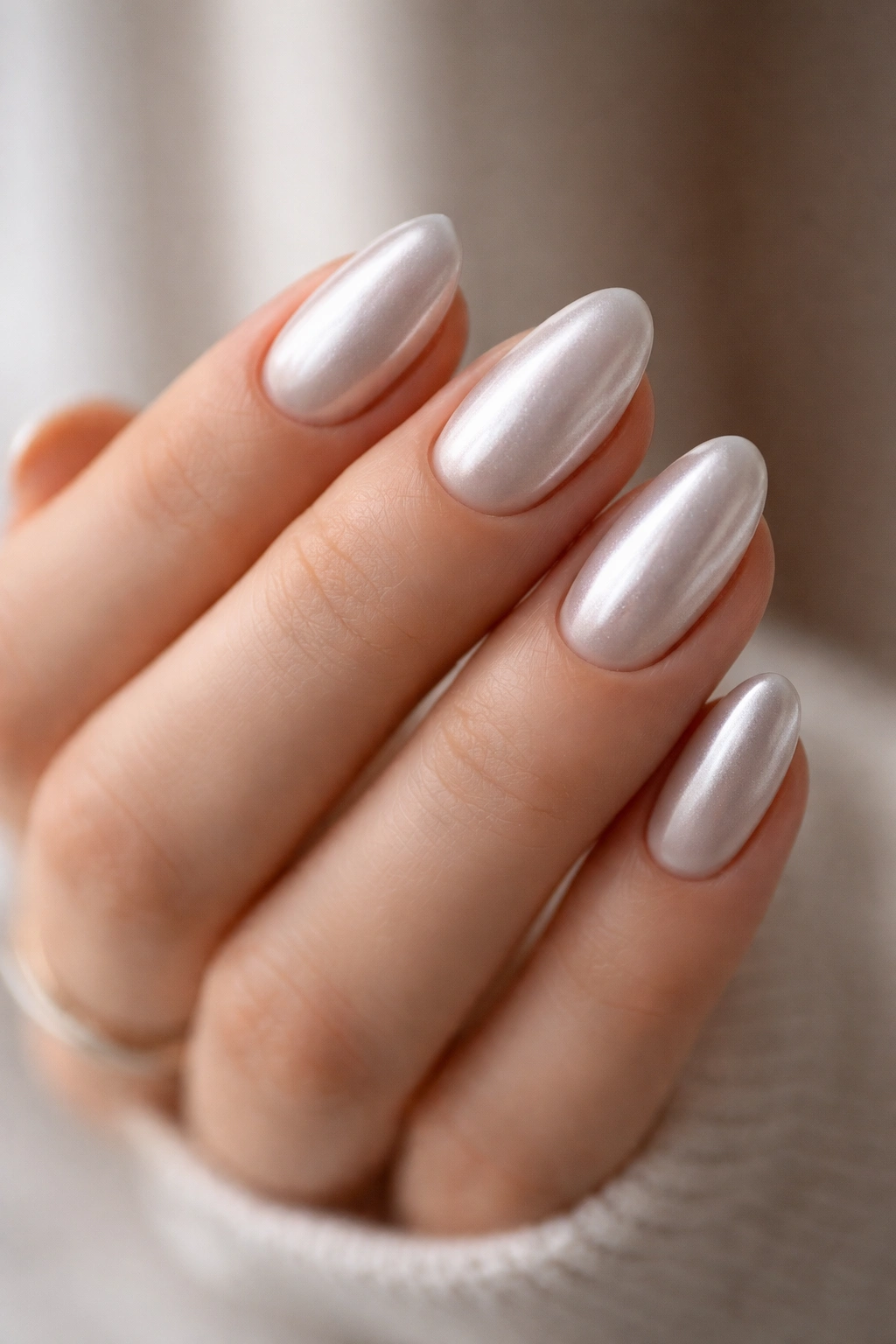 Close-up of pearl silver almond nails with soft luminous finish