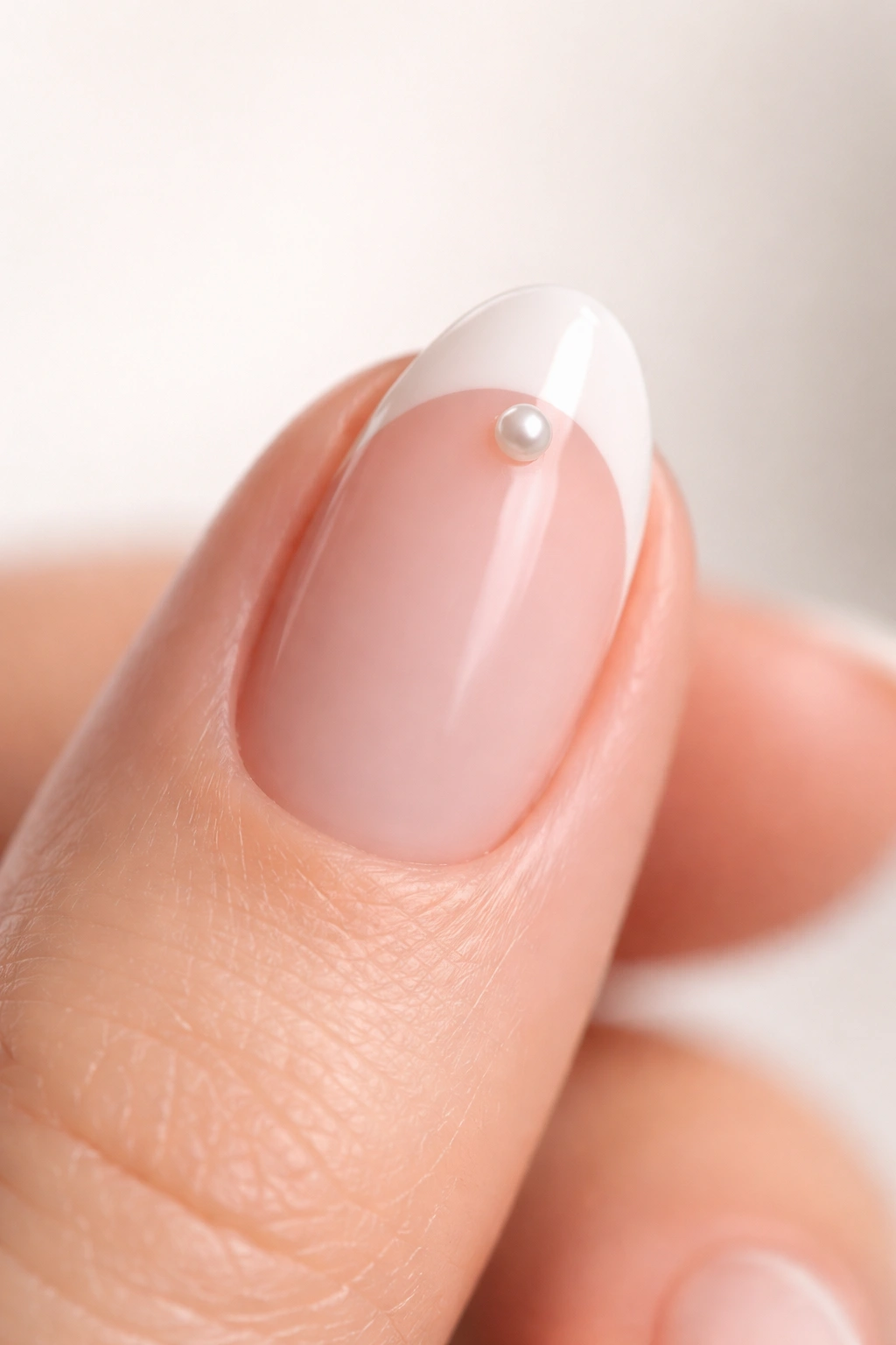 Close-up of a short almond nail with a tiny pearl centered on the smile line.