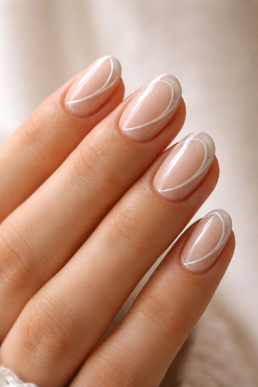Close-up of pearl swirl accents on a nude base short oval nails