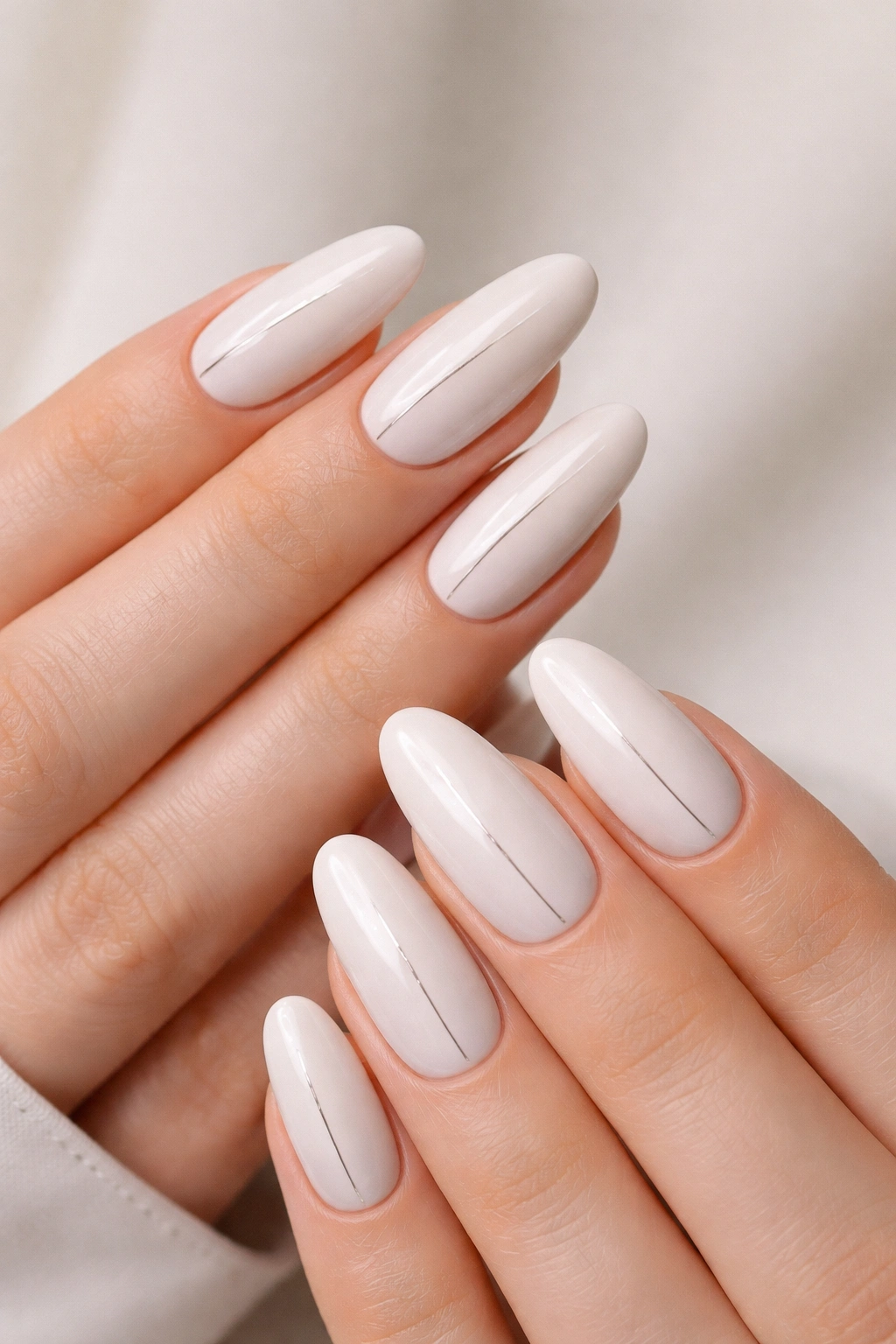 Close-up of pearl-white long oval nails with a single minimal line