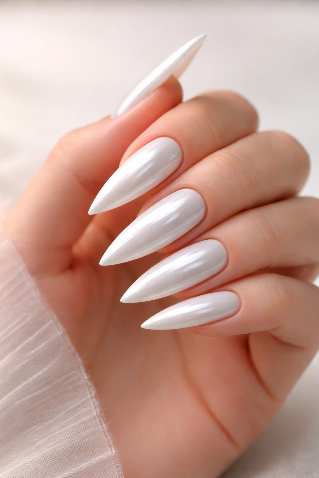 Close-up of pearl white stiletto nails with glossy shine on a neutral background