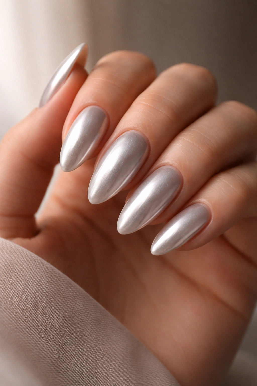 Close-up of pearlized silver almond nails with liquid sheen