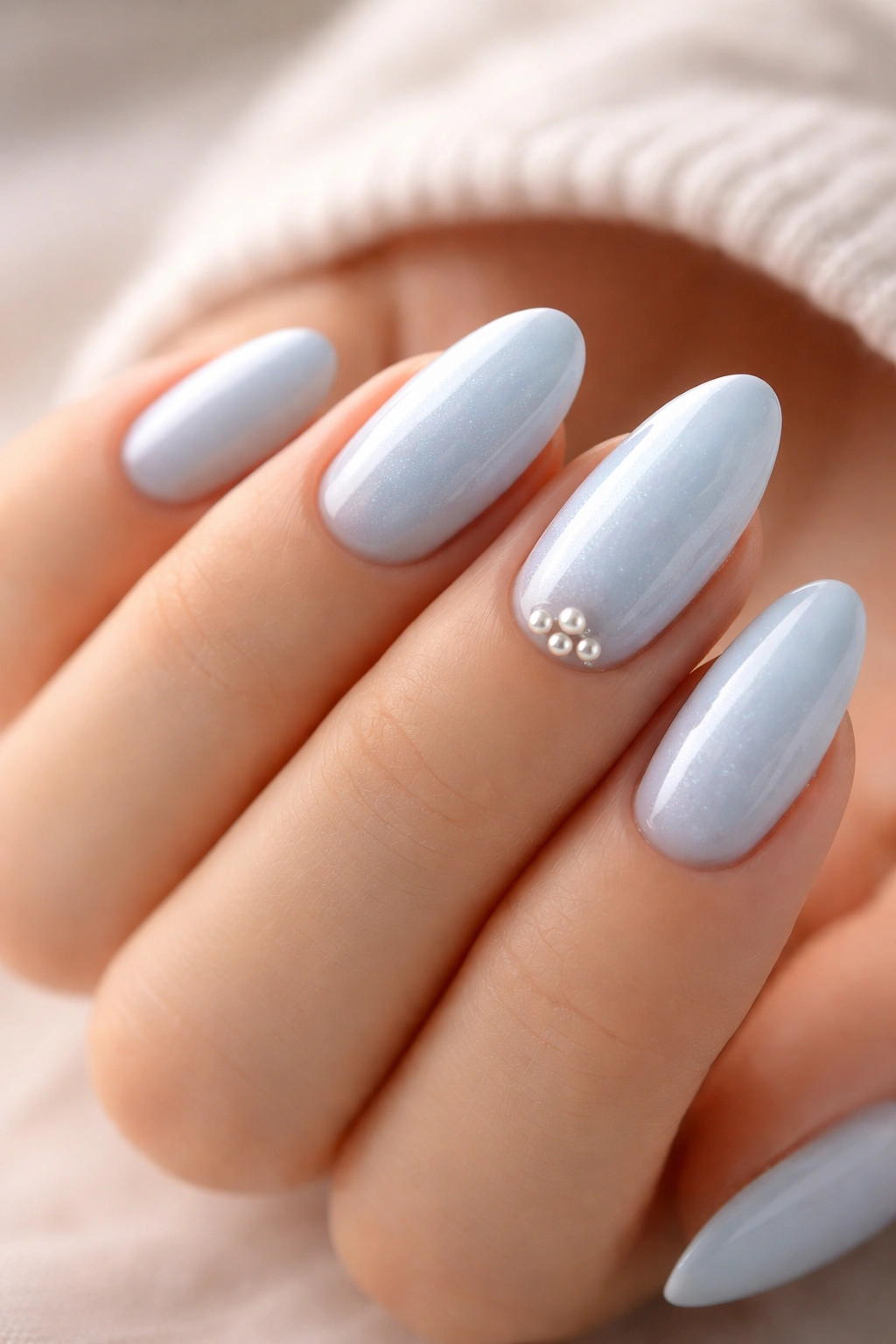 Close-up of icy blue nails with pearl accents on an accent nail
