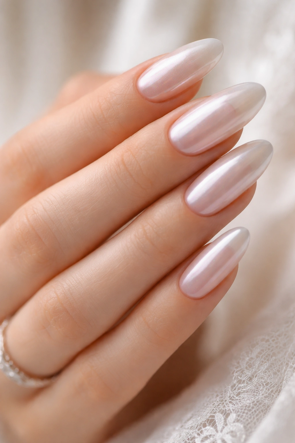 Long oval nails with pale pink base and pearly chrome overlay.
