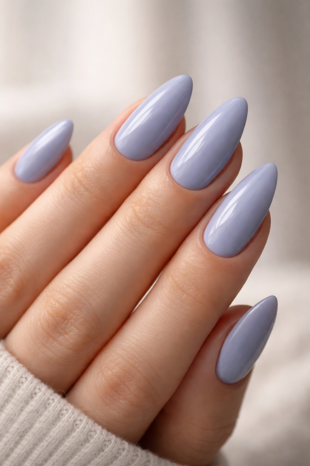 Close-up of periwinkle almond nails in a soft blue-gray hue.