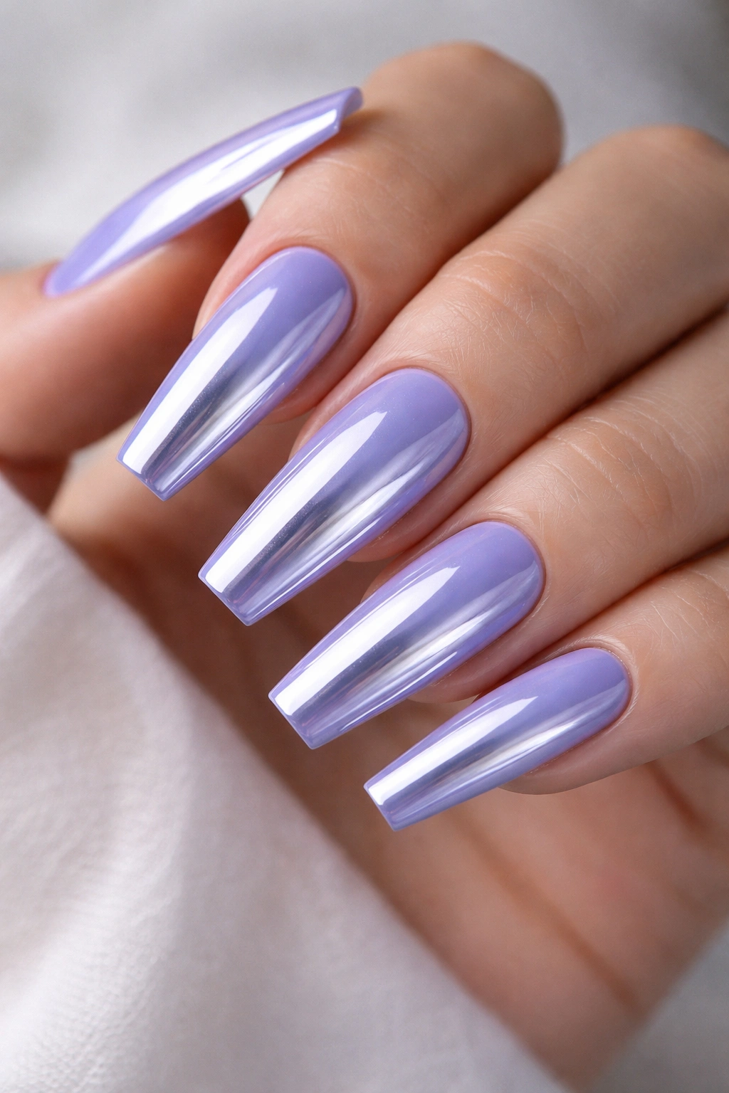 Close-up of light periwinkle chrome nails on long coffin shape with reflective blue-purple chrome