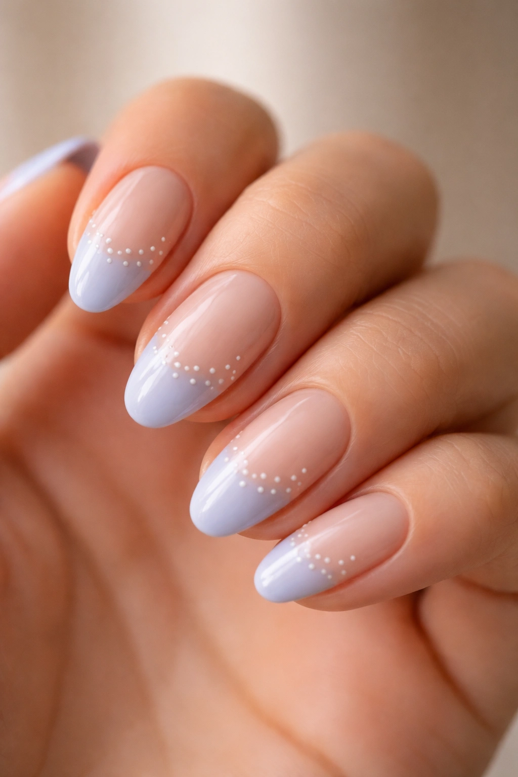 Close-up of a short almond nail with pale periwinkle tip and dotted base detail