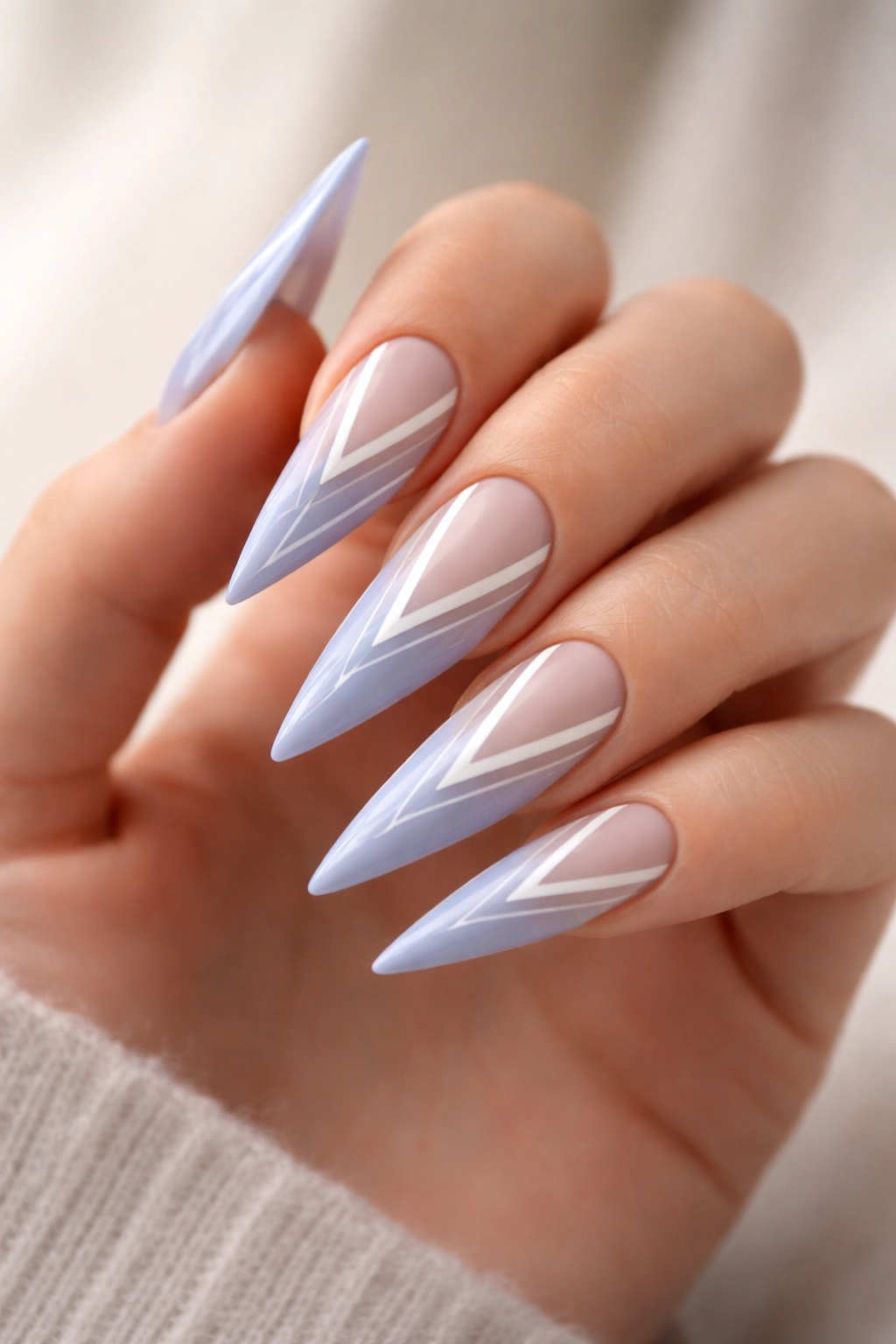Close-up of periwinkle stiletto nails with negative-space geometric lines on a bare hand