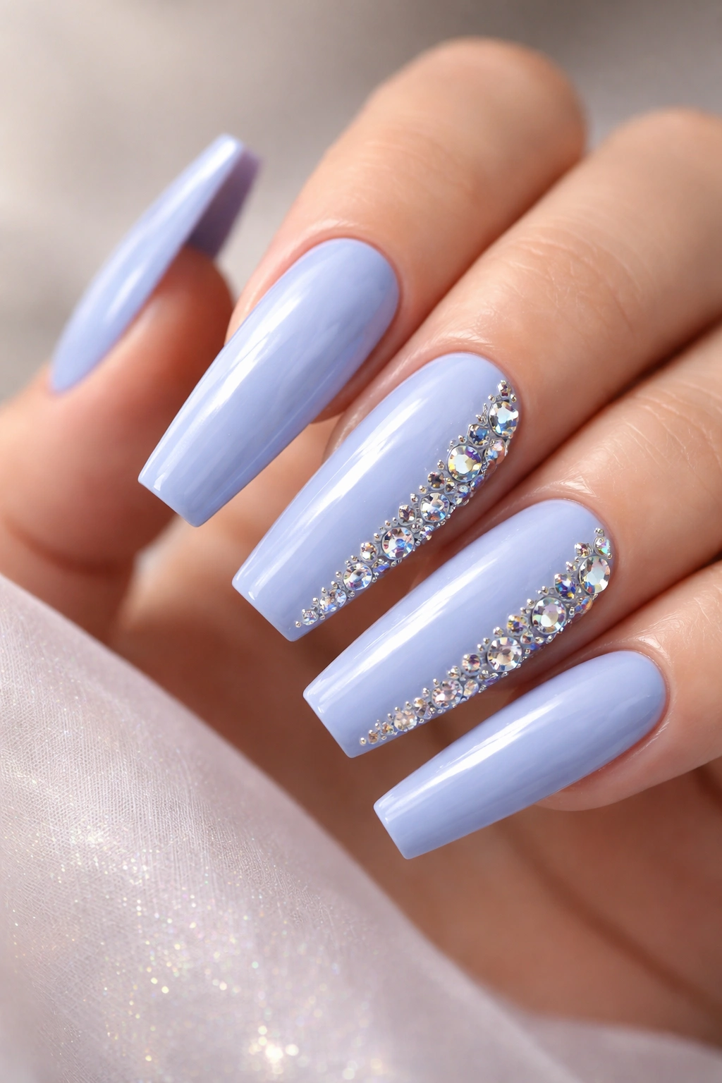 Periwinkle coffin nails with 3D rhinestones on a neutral backdrop