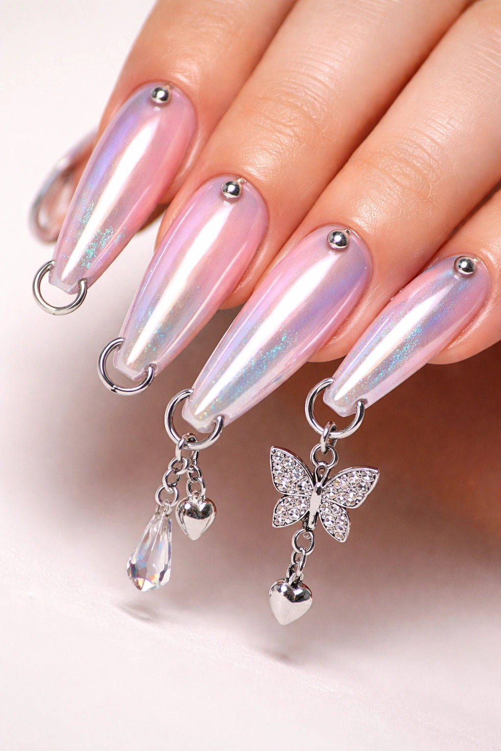 Close-up of pierced acrylic nails with hoops and charm
