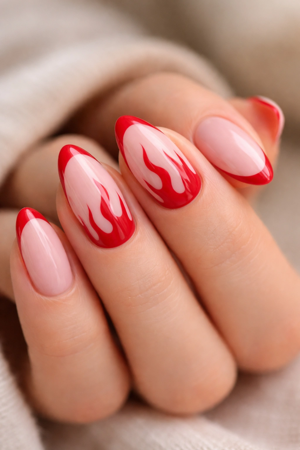 Close-up of pink almond nails with red flame tips on two accent nails