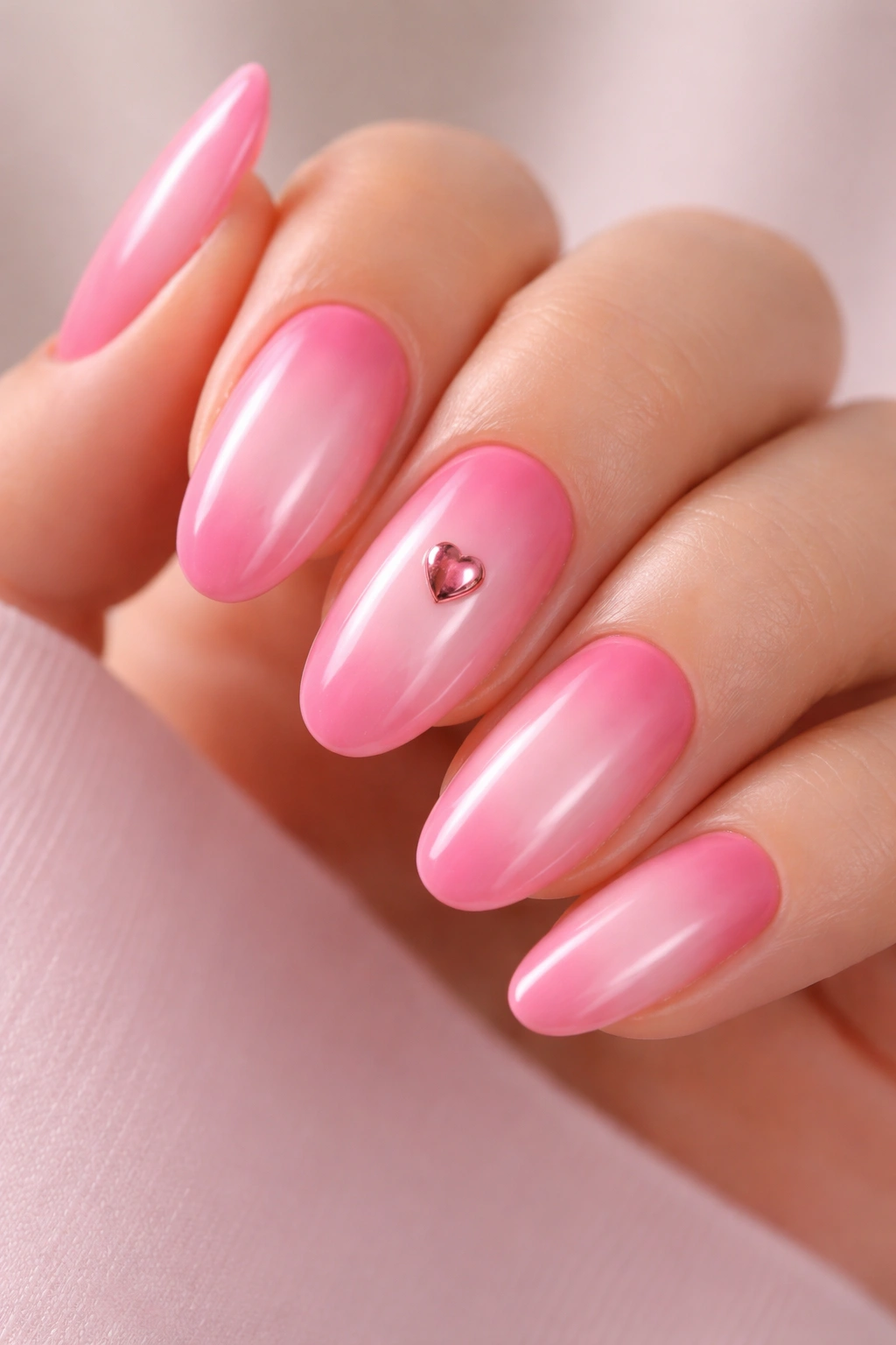 Soft pink aura nails with a central heart accent.