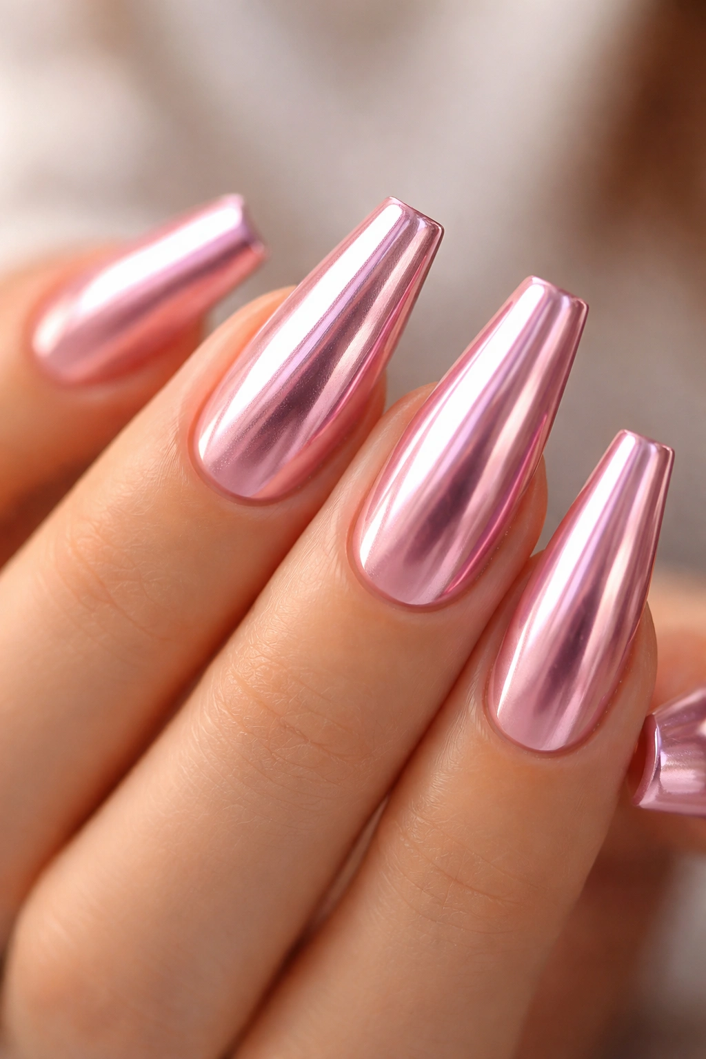 Close-up of pink chrome ballerina nails with flat tapered tips and glassy shine