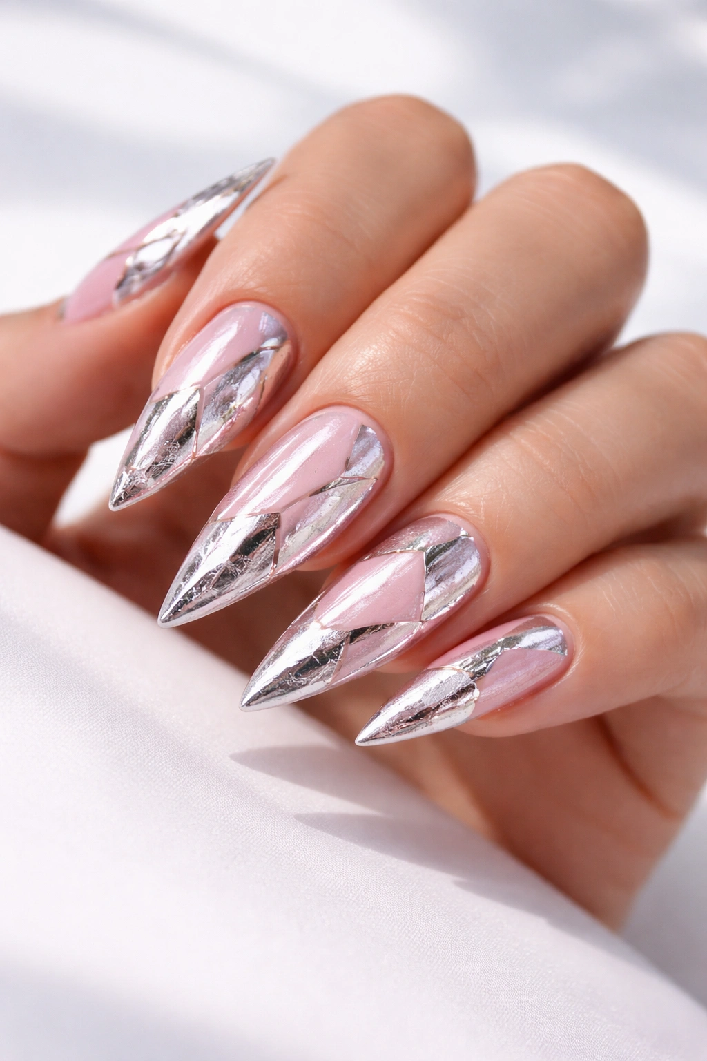 Close-up of pink stiletto nails with silver foil geometric art