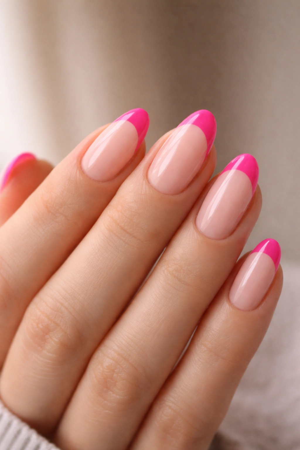 Close-up of hot pink French tips on short almond nails with a sheer base