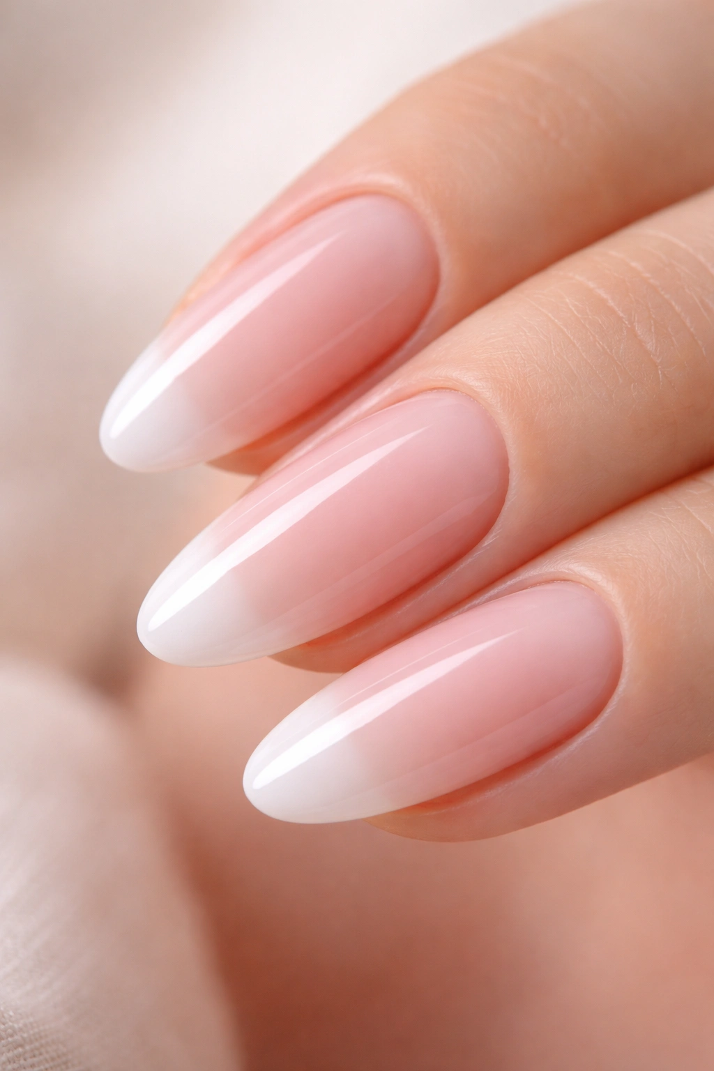 Close-up of a short almond nail with sheer pink gradient fading into white tip.