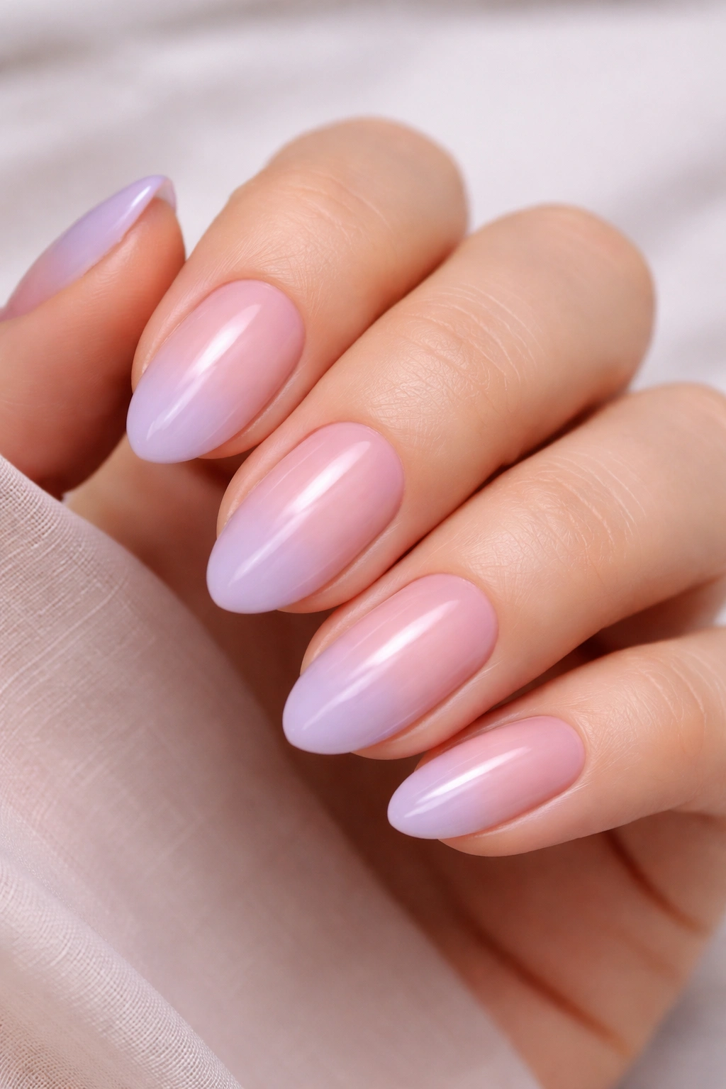 Close-up of short almond nails with pink to lilac ombre