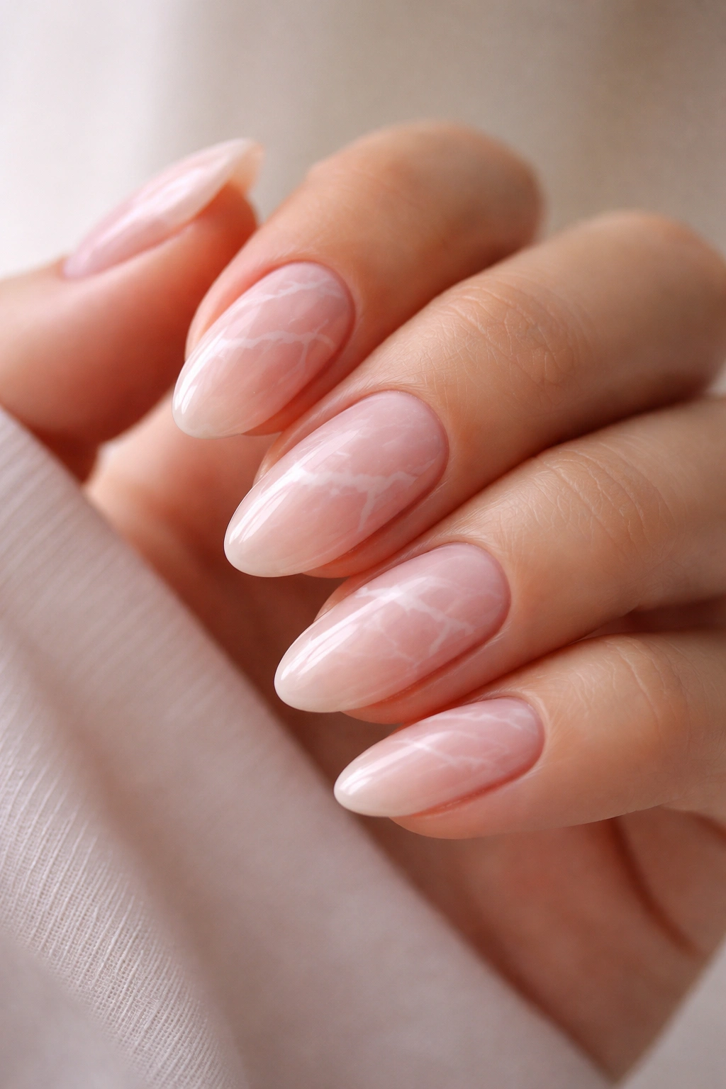 Soft pink marble nails on short almond tips with wispy white veins