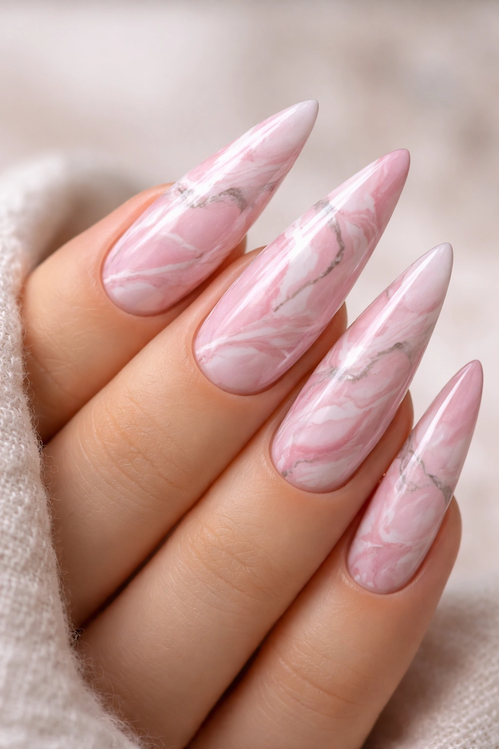 Close-up of pink marble stiletto nail with gray veining
