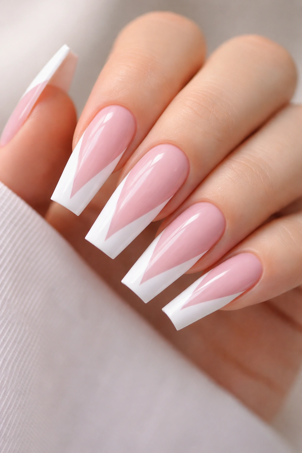 Close-up of coffin nails with soft pink base and white geometric tip shapes