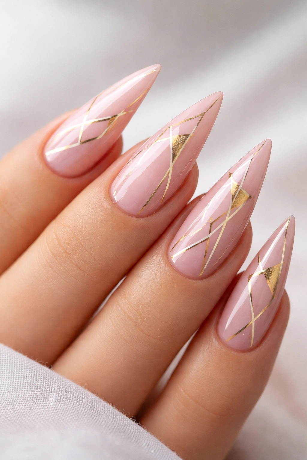 Close-up of pink nails with gold geometric patterns on stiletto nails