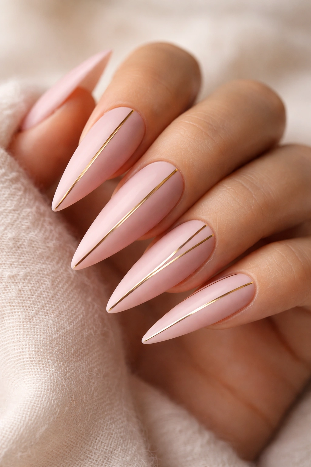 Matte pink nails with gold stripes on stilettos