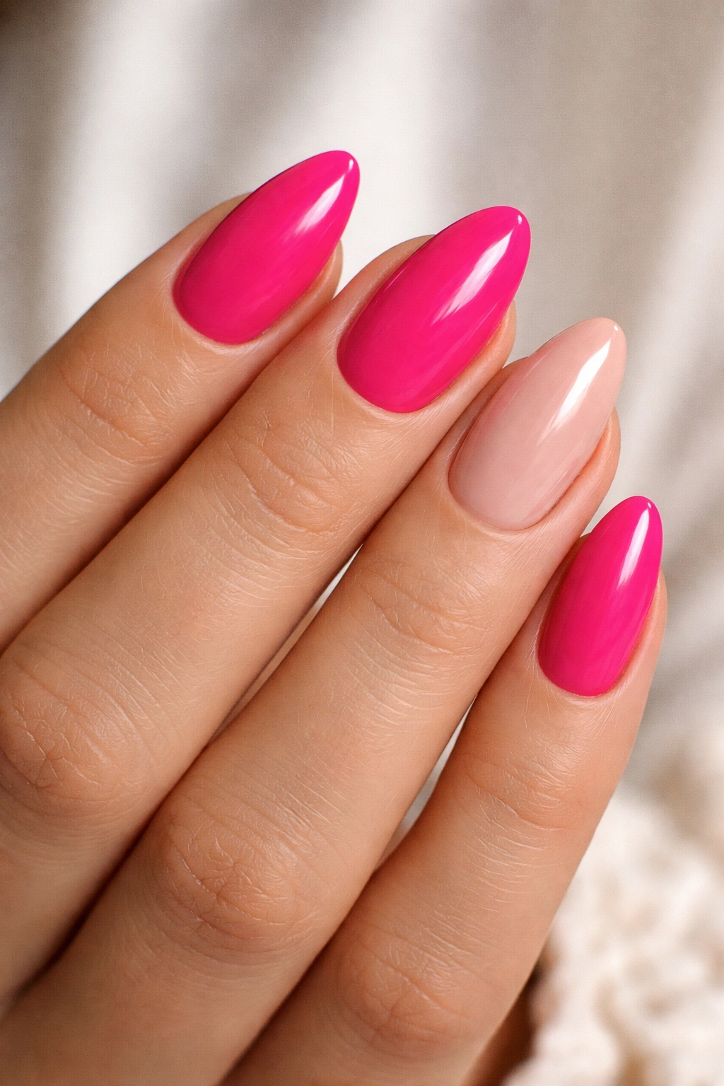 Close-up of hot pink almond nails with a nude accent nail