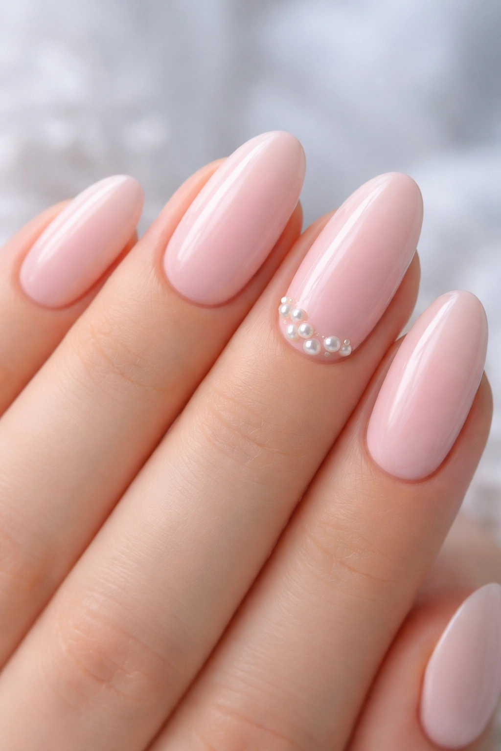 Light pink oval nails with pearl accents on one or two nails