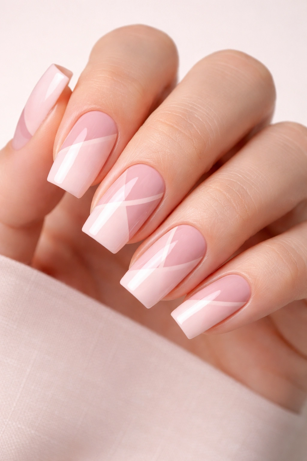 Close-up of pink square nails featuring geometric negative-space patterns