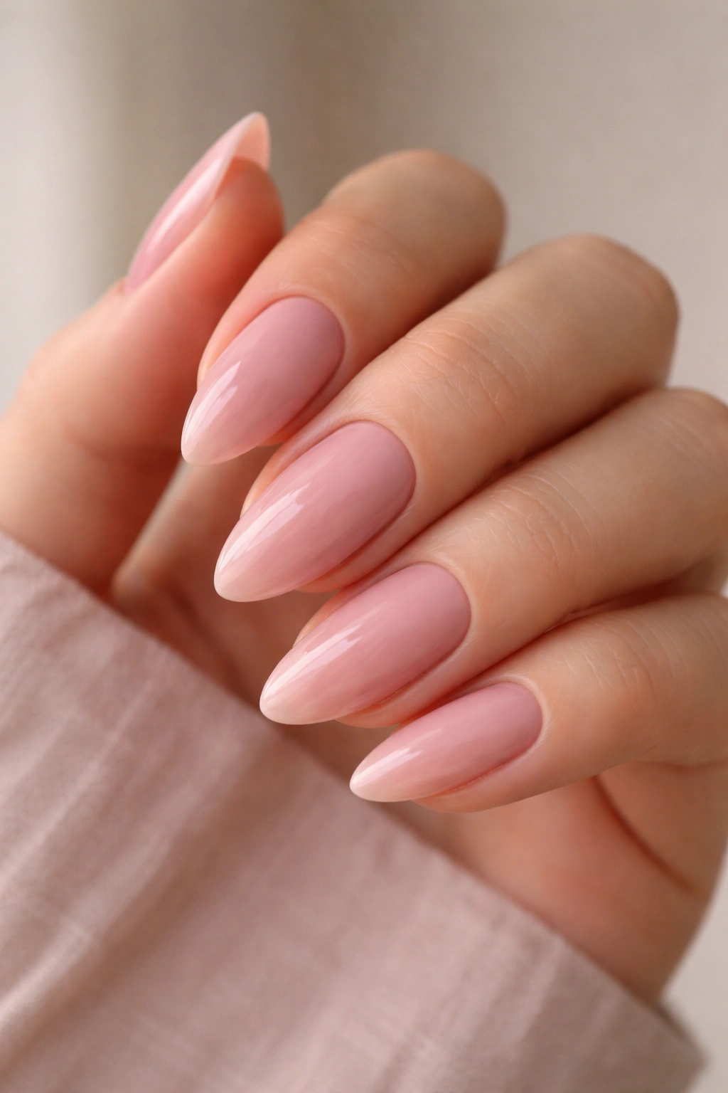 Close-up of pink undertone nude almond nails on a hand