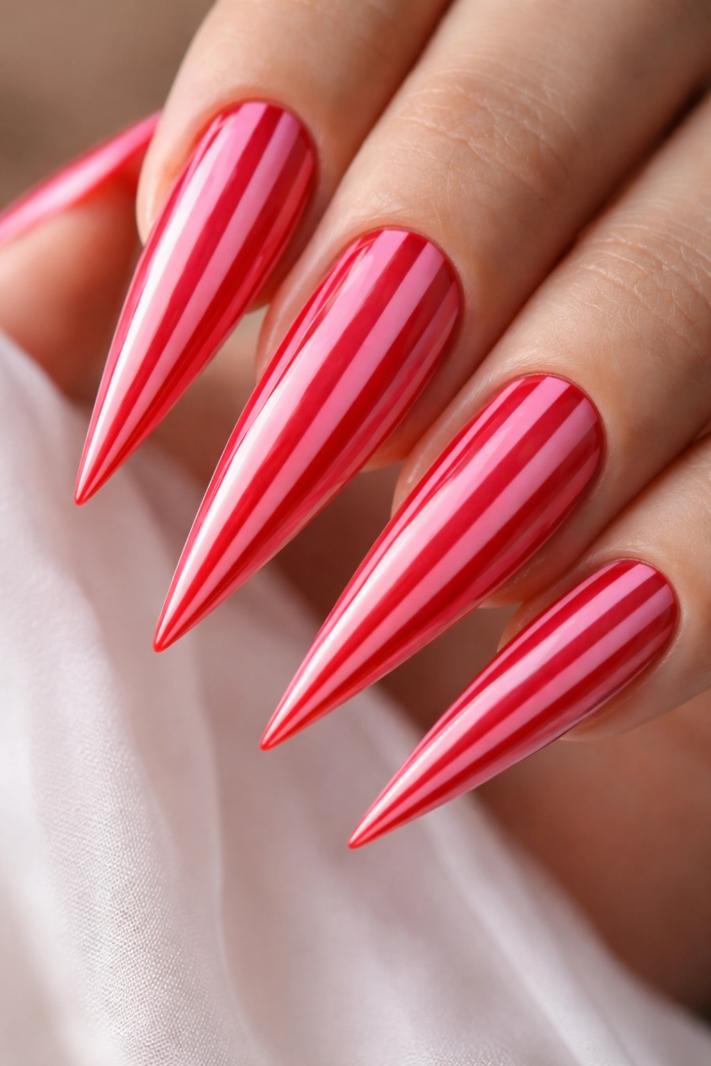 Close-up of pink and red striped stiletto nails with vertical stripes
