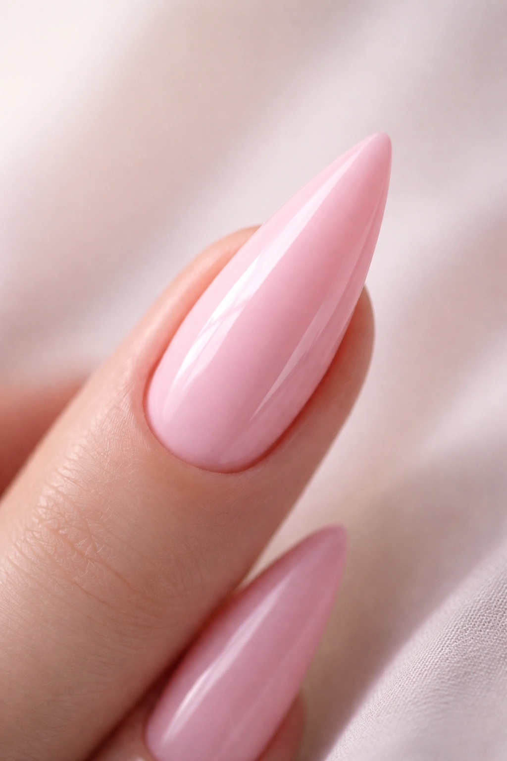 Close-up of a glossy baby pink stiletto nail on neutral background
