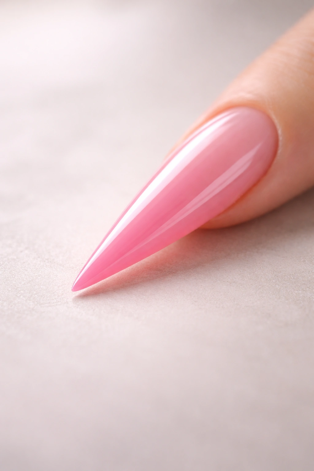 Single pink stiletto nail on a neutral surface representing versatility