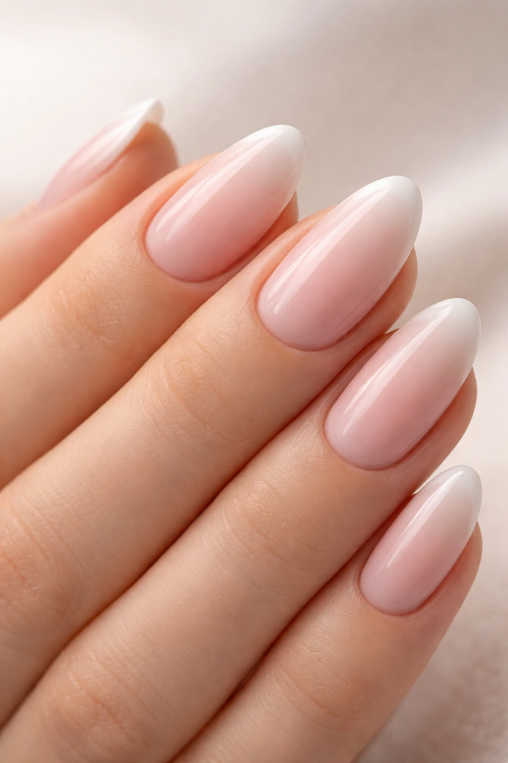 Close-up of short almond nails with pink to white fade and clean edge