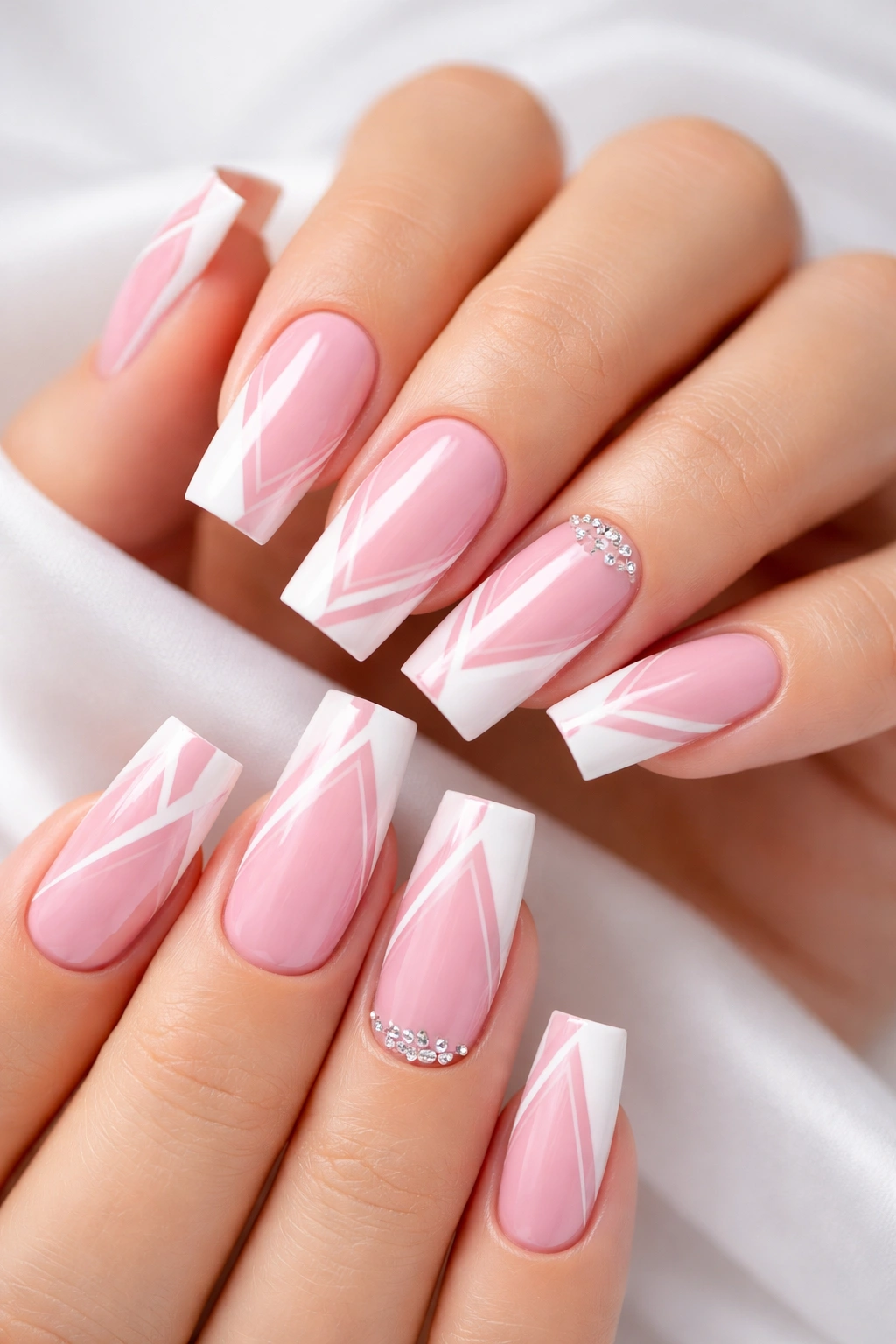 Close-up of pink and white nail art with geometric patterns on square nails