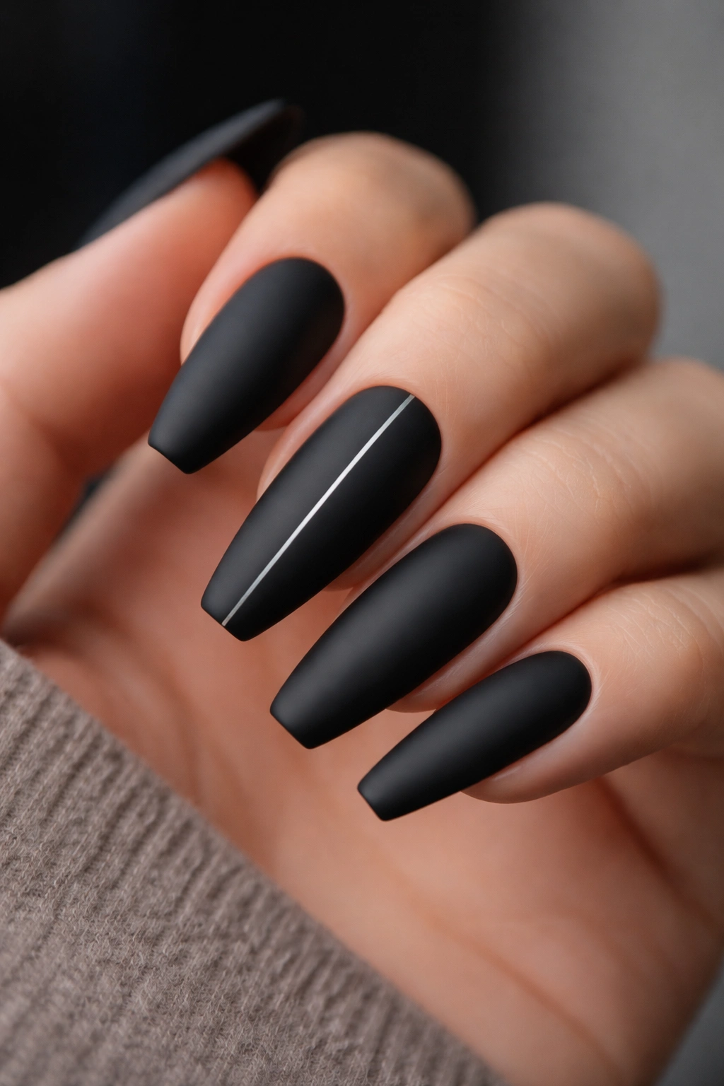 Matte black nails with a thin silver pinstripe down the center