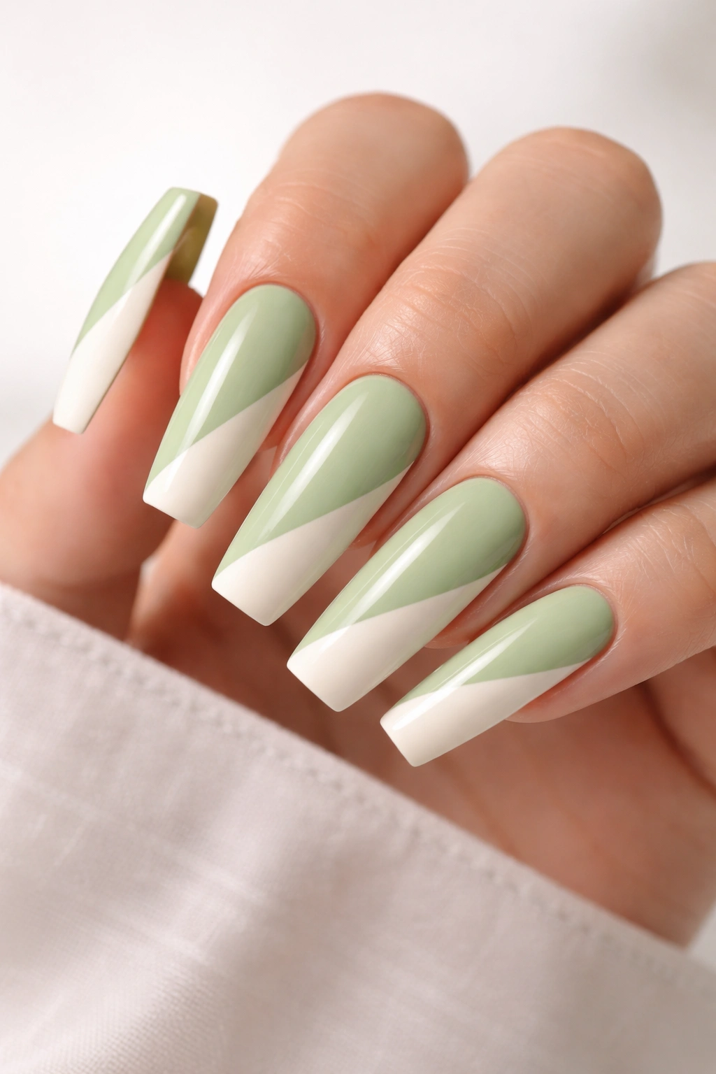 Close-up of pistachio and cream color-block nails on a long ballerina manicure