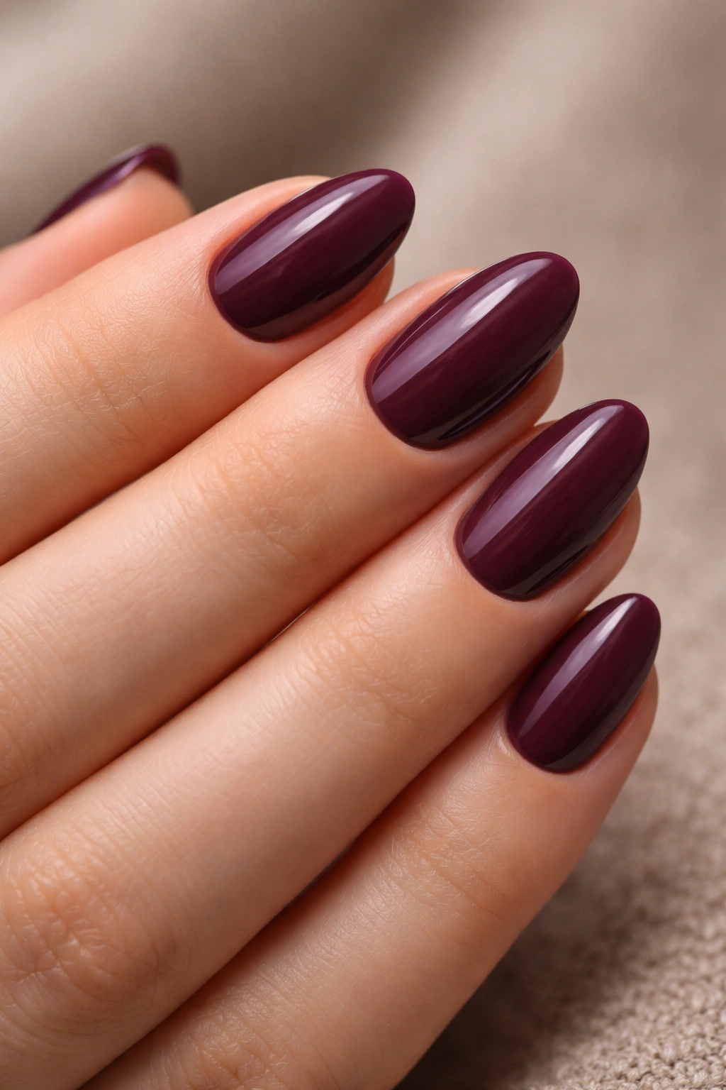 Close-up of plum almond nails on a hand with soft gloss