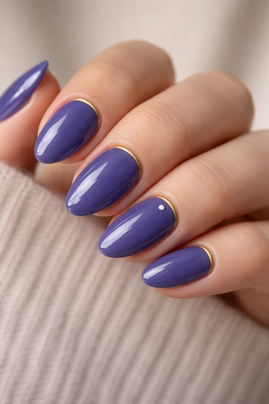 Close-up of short almond nails plum-blue with tiny gold line and white dot accents
