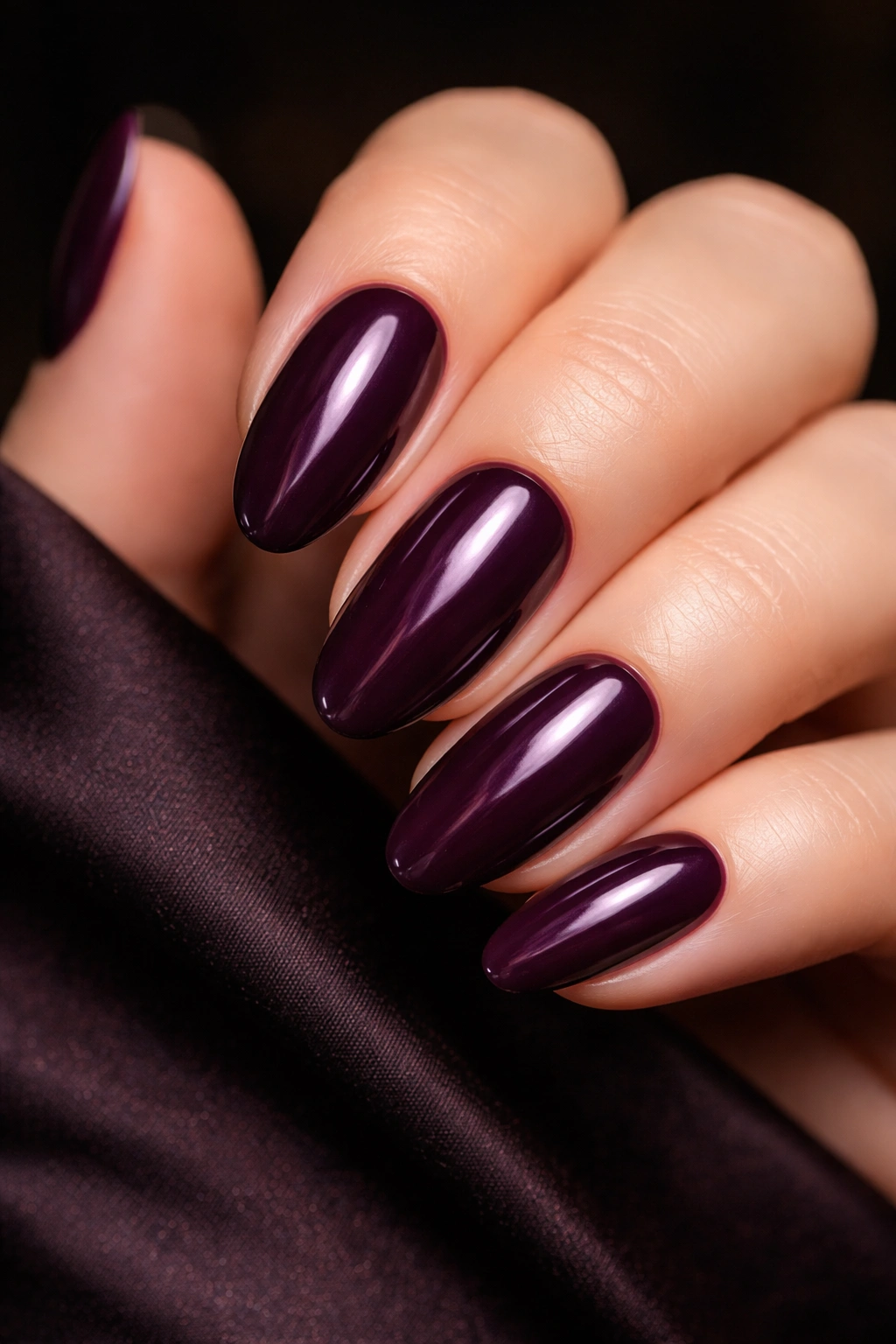 Close-up of deep plum nails on a hand with warm lighting