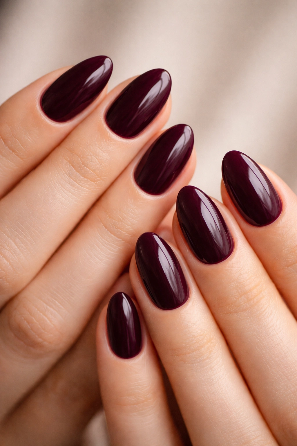 Close-up of hands showing deep plum short almond nails