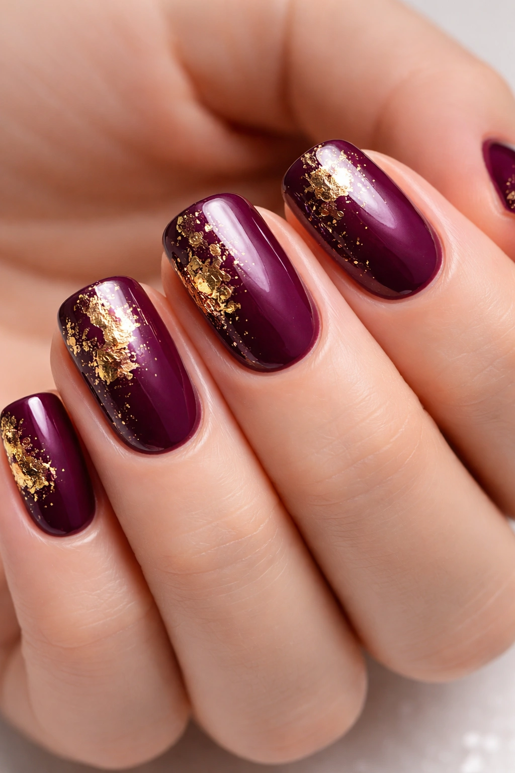 Close-up of plum nails with gold foil texture