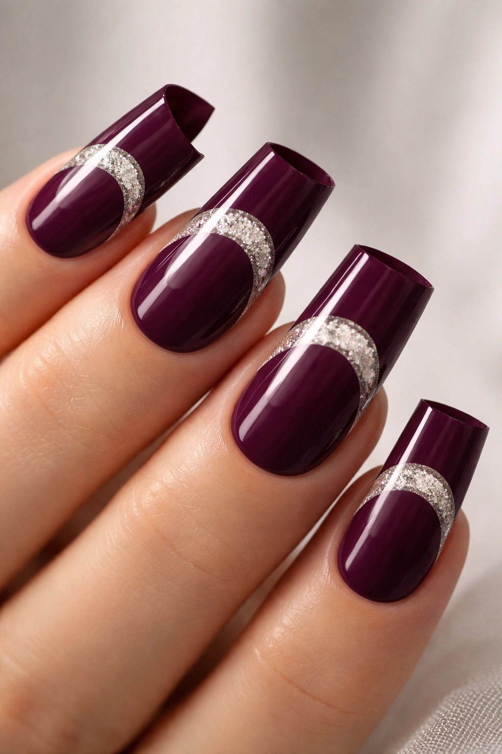 Deep plum nails with negative-space half-moon at tips