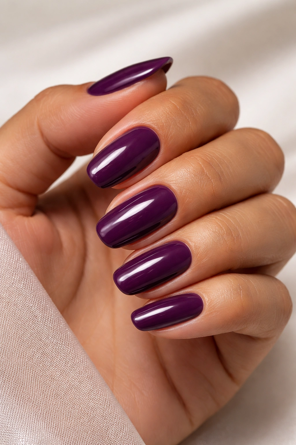 Close-up of plum nails on olive skin.
