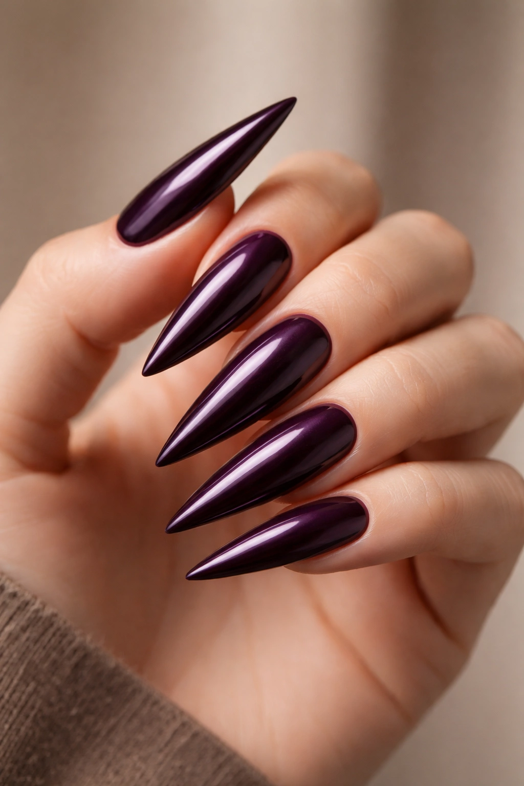 Close-up of rich plum purple stiletto nails with glossy finish