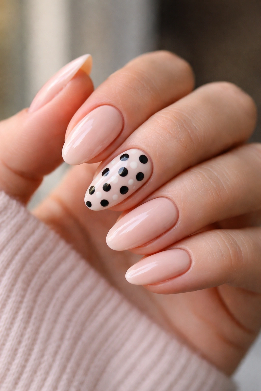 Close-up of accent nails with black and white polka dots on nude base