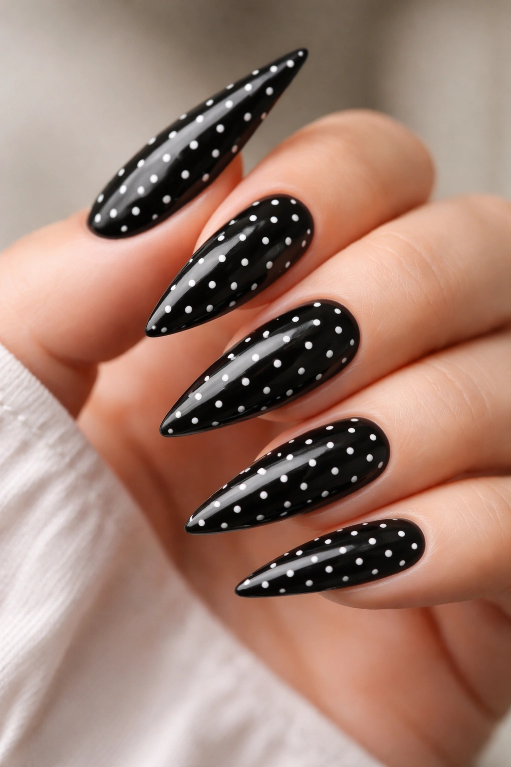 Close-up of black stiletto nails with tiny white polka dots.
