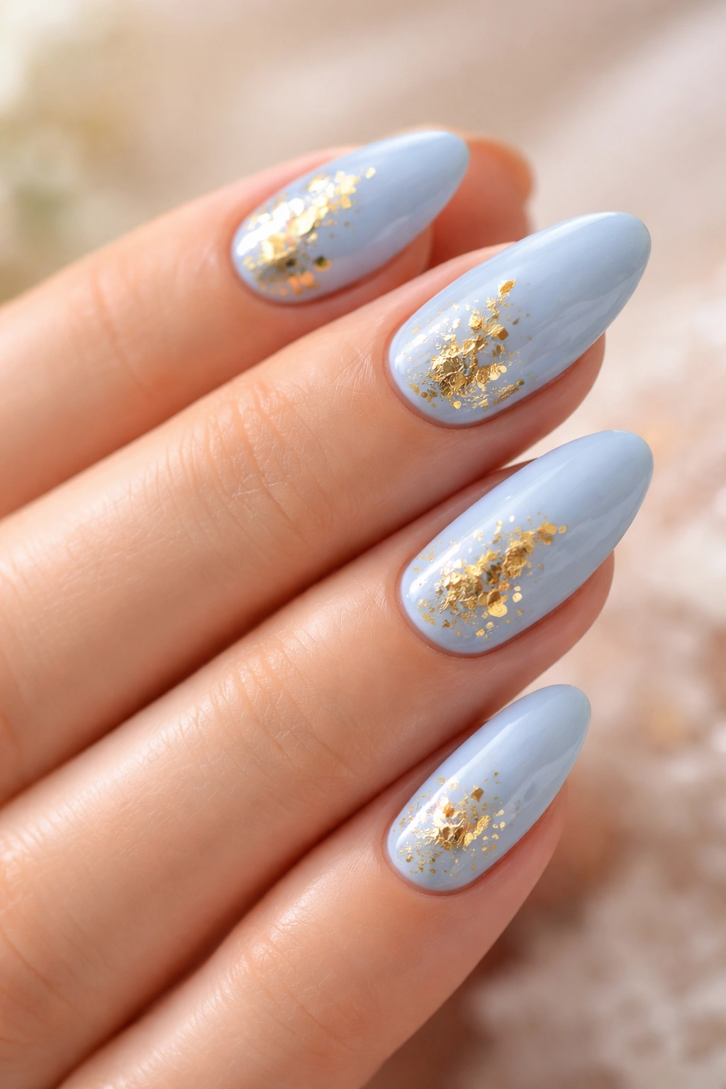 Close-up of powder blue nails with gold foil accents.